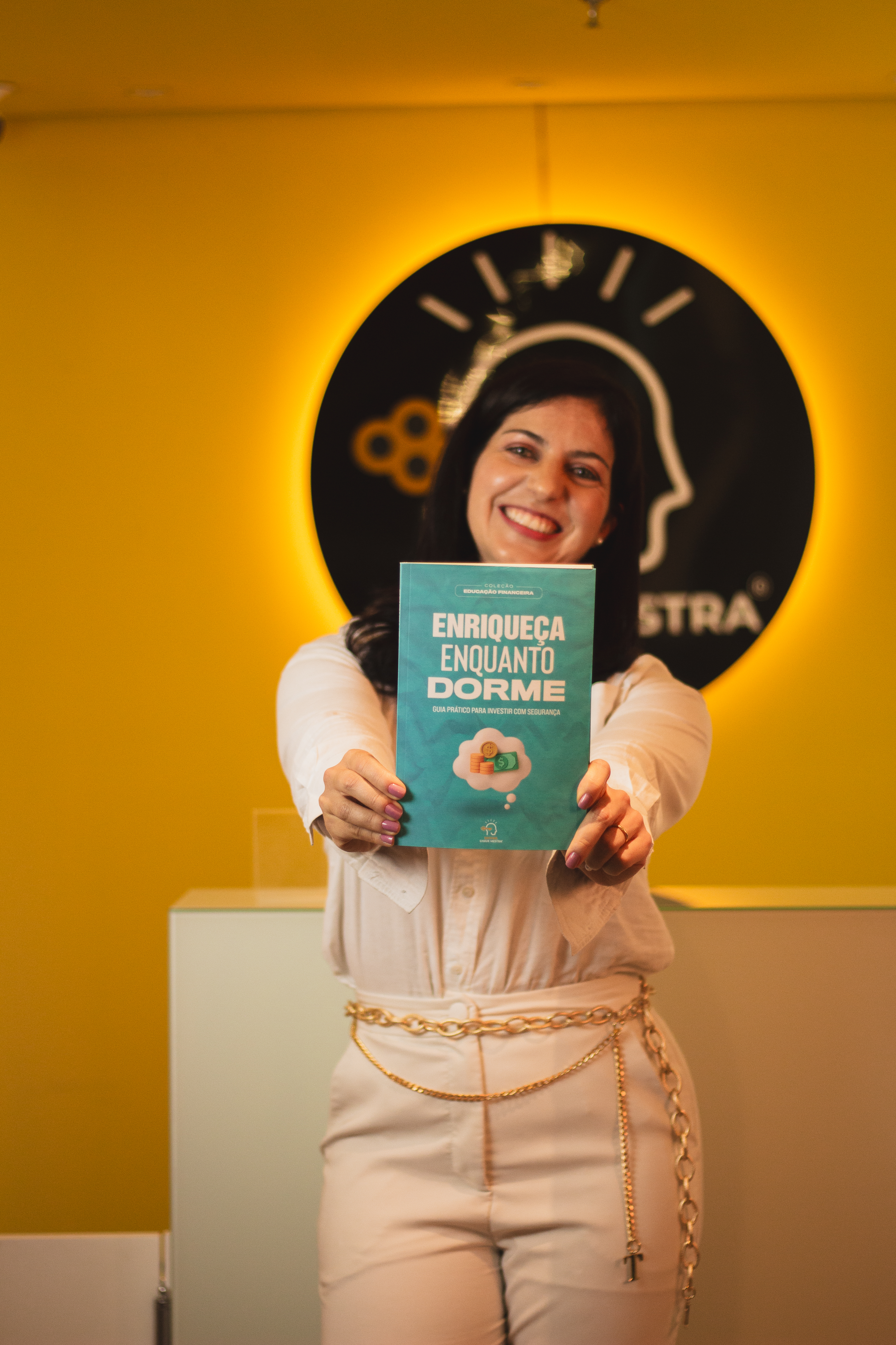 Flávia Schuscimann segurando o livro Enriqueça Enquanto Dorme